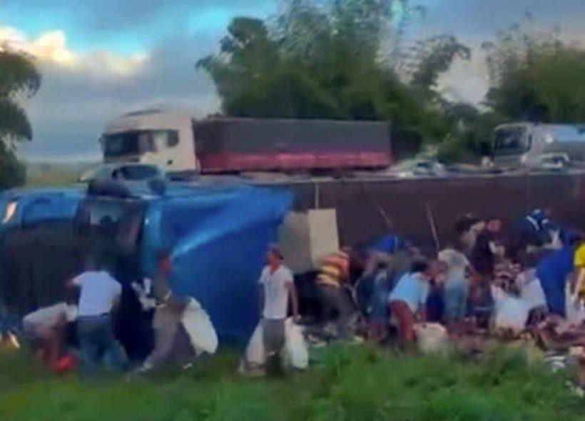 Caminhão sai da pista, tomba e carga de cerveja é saqueada na BR-324, na região de Feira de Santana